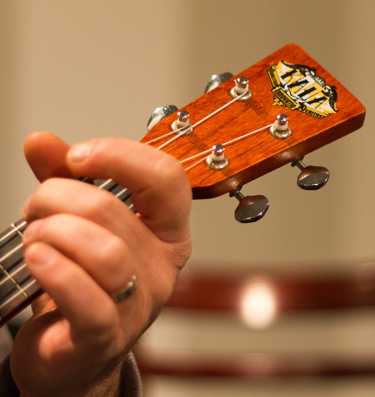 White hand playing ukulele