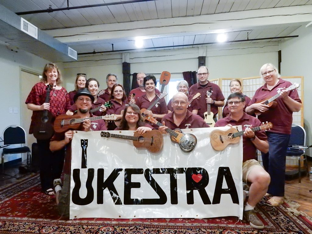 Ukestra group with ukuleles and large banner